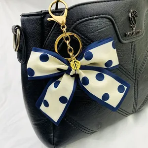 Détail d'un élégant porte-clés foulard en soie à pois bleus et blancs sur un sac noir