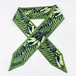 Vue détaillée d'un foulard étroit en soie à imprimé botanique vert avec motifs de fougères