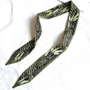 Vue détaillée d'un ruban à cheveux en soie avec motif de feuilles vert foncé pour sacs
