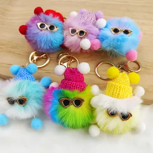 Selection of six colorful fuzzy pom-pom keychains featuring cute sunglasses and knitted hats