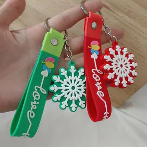 Détail des porte-clés flocon de neige en silicone rouge et vert avec lanière Love blanche