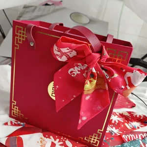 Red souvenir gift bag featuring a leather handle and a festive Christmas silk scarf bow