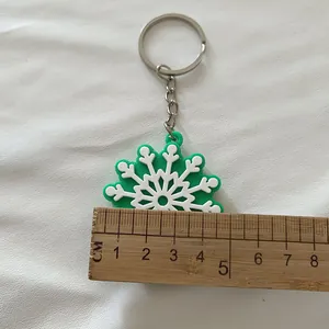 Gros plan d'un porte-clés flocon de neige en silicone vert et blanc mesuré par une règle