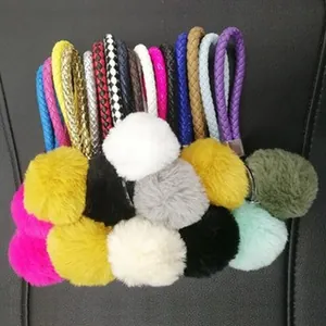 Close-up detail of multi-color plush pom-pom keychains featuring braided leather straps