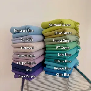 Detailed view of multiple soft knitted scarves stacked by color in vibrant blue and green tones
