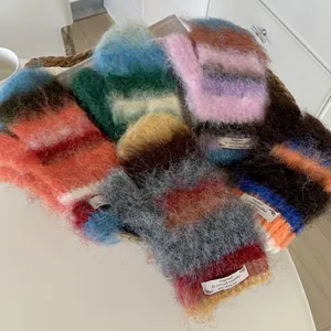 Macro detail of various colorful fuzzy mohair mittens presented in a woven basket