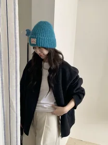 Detailansicht einer blauen warmen Strickmütze mit Bella-Etikett für die Wintermode