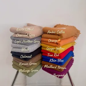 Detailed view of stacked thick knitted scarves in various solid colors for winter warmth