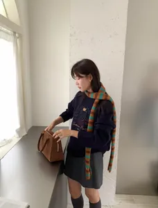 Bufanda larga de punto a rayas estilo Y2k en una modelo en un entorno interior minimalista