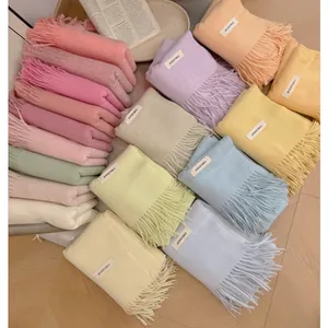 Detailed view of colorful pastel knitted scarves with fringe and brand labels