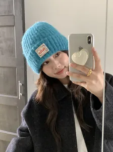 Junge Frau mit einer gemütlichen blauen Strickmütze mit Stofflabel in einem Spiegel-Selfie