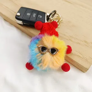 Detailed view of a colorful fuzzy keychain charm with sunglasses and a red hat