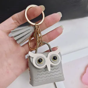 Vue détaillée d'un joli porte-clés hibou en cuir gris avec pompon décoratif et fermoir doré