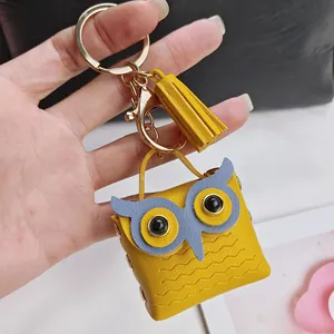 Gros plan d'un joli porte-clés hibou en cuir jaune avec pompon et mousqueton doré brillant
