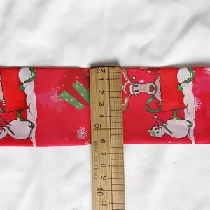 Detailed view of red Christmas themed silk ribbon showing 5cm width with a ruler