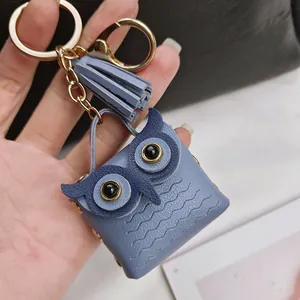 Vue détaillée d'un porte-clés chouette en cuir bleu avec pompon et accessoires en métal doré