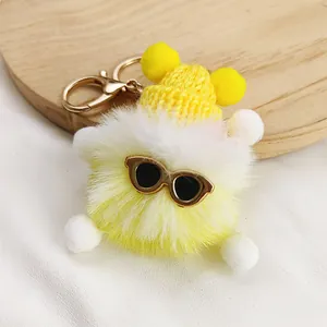 Detailed view of cute yellow and white plush keychain featuring sunglasses and a tiny hat