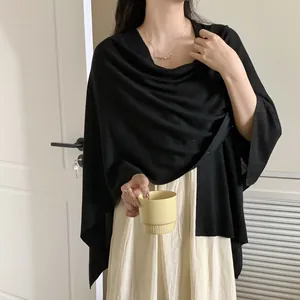 Donna elegante che indossa uno scialle nero leggero per la protezione solare in ufficio