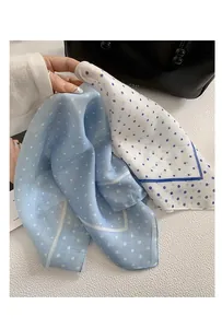 Close-up detail of lightweight blue and white polka dot silk-like headscarf with soft texture