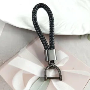 Close-up detail of a premium black braided leather keychain with gunmetal horseshoe buckle