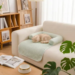 Detail shot of a light green quilted pet cooling mat on a beige sofa with a sleeping cat