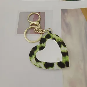 Gros plan du porte-clés miroir cœur imprimé léopard avec détails en métal doré.