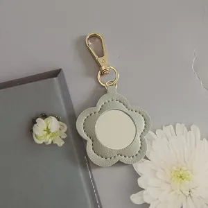 Elegant portable flower-shaped PU leather mirror keychain with gold lobster clasp.