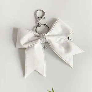 Elegante portachiavi a fiocco in nastro bianco glitterato con strass e anello argento.