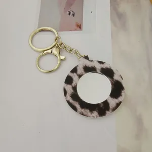 Détail d'un porte-clés miroir portable à imprimé léopard avec une finition dorée élégante.