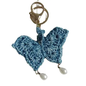 Delicate blue handmade crochet butterfly keychain featuring elegant white pearl drops