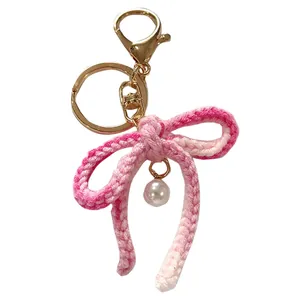 Handmade pink crochet bow keychain featuring a pearl pendant and gold hardware