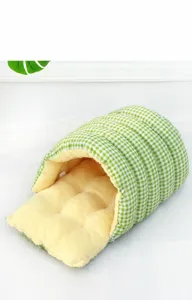 Primer plano de una cama túnel para mascotas a cuadros verdes con forro de felpa suave.