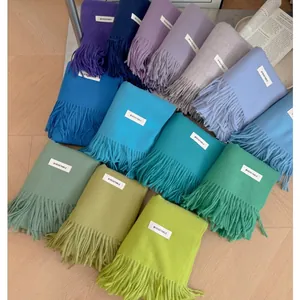 Detailed view of colorful solid knit scarves with tassels and white labels