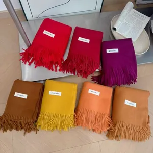 Close-up of assorted solid color thick knitted scarves with elegant fringe details