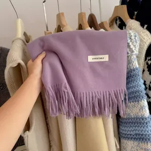 Detailed shot of soft purple knitted scarf featuring elegant tassels and a decorative tag