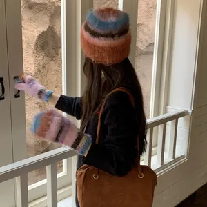 Rear view of model wearing a multi-colored fuzzy beanie and matching winter mittens