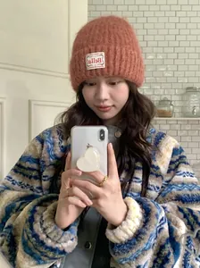Nahaufnahme einer orangefarbenen Strickmütze im koreanischen Stil mit weißem Etikett