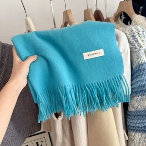 Close-up of a vibrant blue knit scarf with soft fringe detail and brand label.