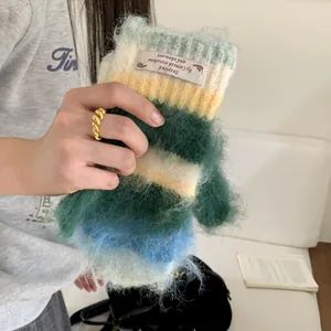 Detailed view of the fuzzy texture and 'Cornish sunshine' tag on a colorful knit mitten.