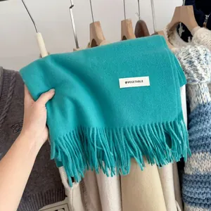 Detail view of a thick blue knitted winter scarf with fringes and a decorative label.