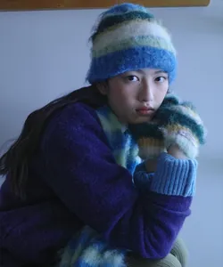 Detailed view of the soft fuzzy striped blue and green beanie and mittens set on a model