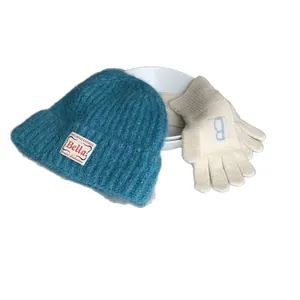 Winterblaue Strickmütze mit Vintage-Patch und passenden weißen Handschuhen im Set