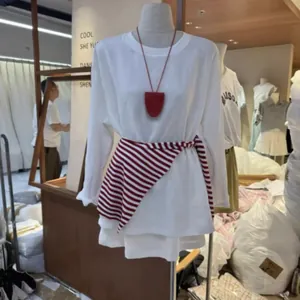 Vista detallada de un accesorio de chal de rayas rojas y blancas en un maniquí.