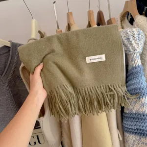 Soft olive green knit scarf detail with fringe edge and white vegetable label tag