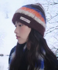 Side view of a cozy striped mohair beanie worn by a model in a snowy winter forest