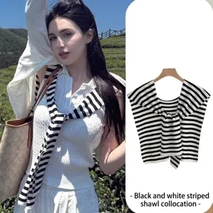 Detalle de un chal ligero a rayas blancas y negras sobre un conjunto blanco