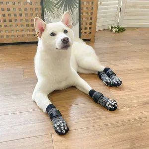White dog wearing non-slip gray knit pet socks with paw print pattern on wood floor
