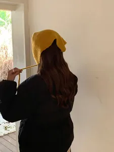 Back view of a person wearing a mustard yellow knitted hood scarf and black puffer jacket