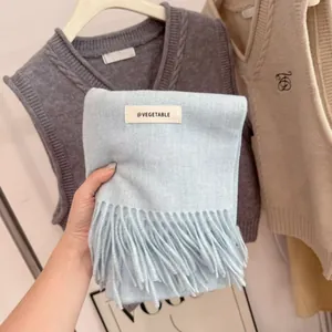 Detailed close-up of a soft light blue knitted scarf with fringes and a woven label
