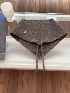 Detailed view of brown knitted multifunctional winter headscarf with tie and button.